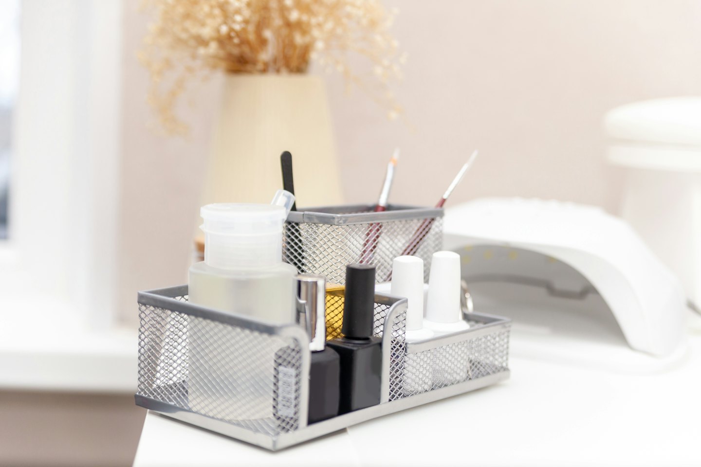 Metalen gaasmandje gevuld met diverse nail art benodigdheden op een tafel.